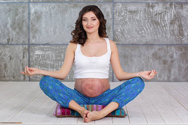 Pregnant girl with mehendi on belly doing meditation stock photo