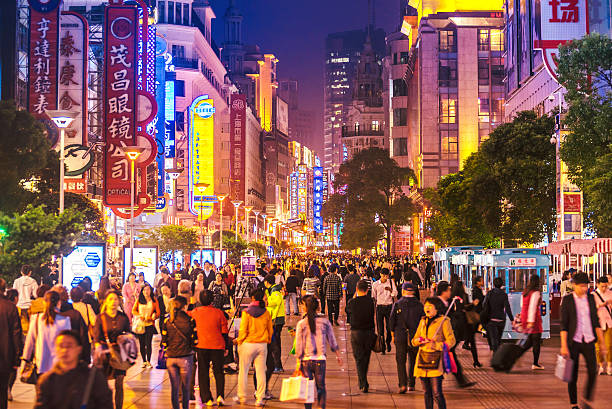 busy Shoppping Street in Shanghai, China at night Crowds walk below neon signs on Nanjing Road. The street is the main shopping district of the city and one of the world's busiest shopping districts. china mall stock pictures, royalty-free photos & images
