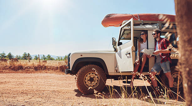 Young couple on road trip reading map for directions