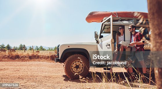 istock Young couple on road trip reading map for directions 519467326