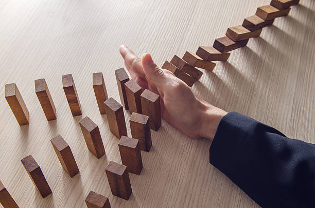 Solution Businesswoman hand stopping the domino wooden effect concept for business. domino effect stock pictures, royalty-free photos & images