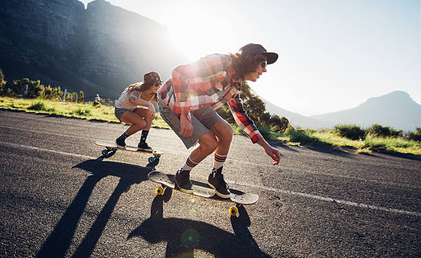 junge freunde longboarden die straße - longboard skating stock-fotos und bilder