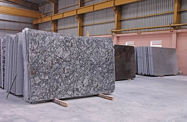 Various shades of Indian polished natural granite floor slabs kept in stacks in storehouse