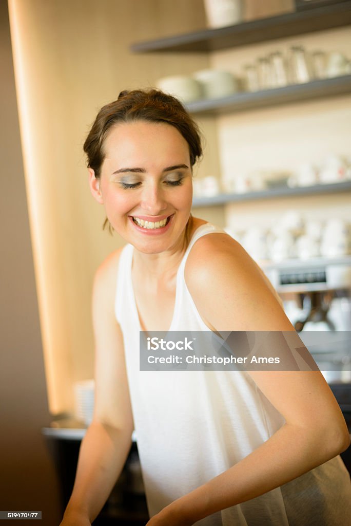 Busy Female Barista Enjoying Her Job Cute female barista busy at work in a bar, happily making drinks and sandwiches. Activity Stock Photo