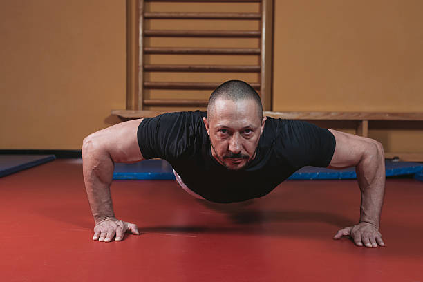 musculado homem fazendo empurre ups em um ginásio - exercising men push ups muscular build imagens e fotografias de stock