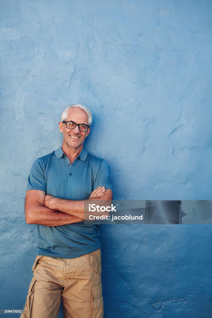 Smiling mature man standing with his arms crossed Portrait of a smiling mature man standing with his arms crossed. Caucasian middle aged man looking away at copy space and smiling. Mature Men Stock Photo