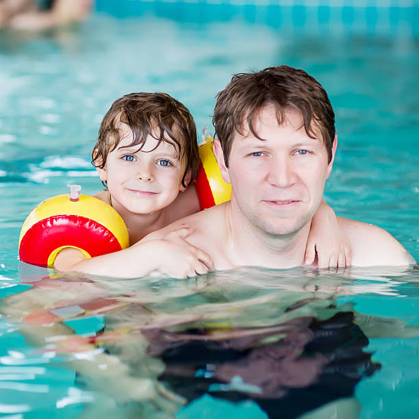 istock Young dad teaching his little son to swim indoors 519471178