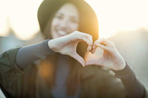 Young hipster woman doing a heart with her hands.