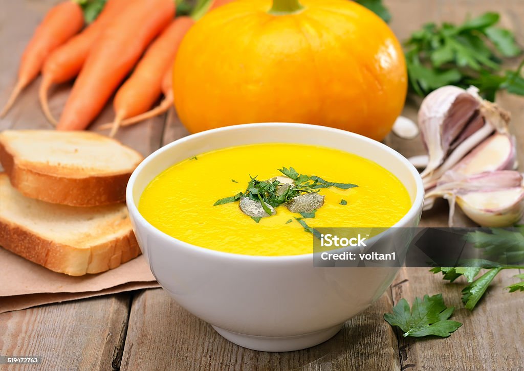 Pumpkin cream soup on wooden table Pumpkin cream soup, fresh vegetables and toast bread on wooden table Appetizer Stock Photo