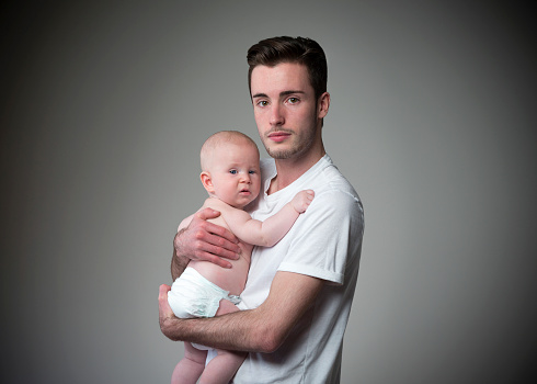 Teen father holding his baby son.