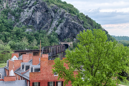 A High Dynamic Range (HDR) rendition of a rooftop view of Harpers Ferry West Virginia.  Old brick buildings in the foreground and railroad tunnel carved in a mountainside in the background.