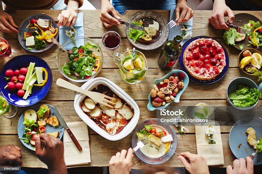 Spring nosh-up People having a rich dinner with fresh vegetables and homemade meal Dinner Party Stock Photo