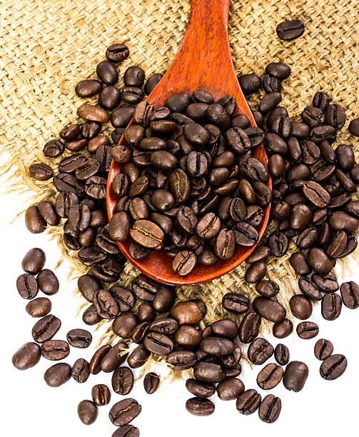coffee beans on sacking and wood spoon, white background