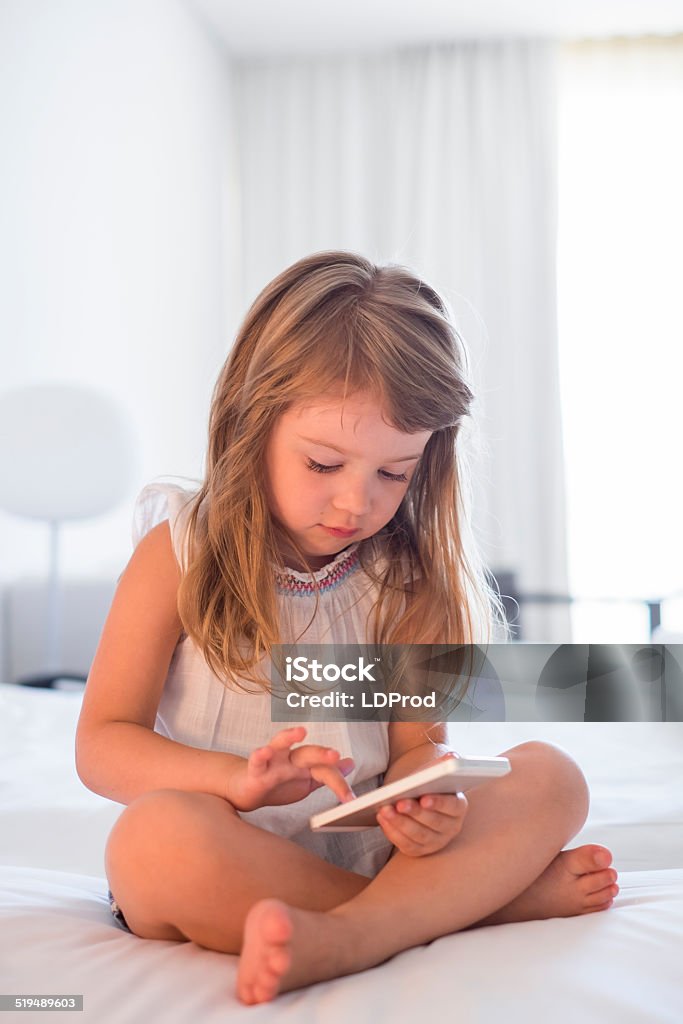Child using mobile phone at home Pretty kid playing game smartphone indoor Baby - Human Age Stock Photo