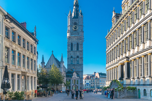 Ghent, Belgium - September 26, 2015: Famous Belfry tower in Gent. A couple pose for wedding photo at the area. Many pedestrians look at them.