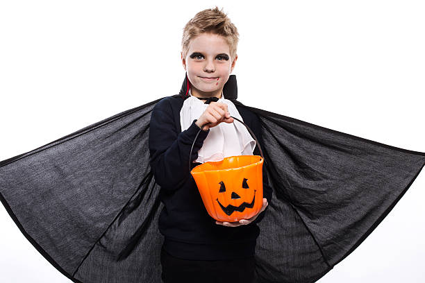 istock Boy with pumpkin basket dressed like vampire for Halloween party 519491605