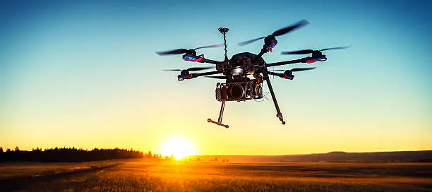 A drone hovers above a golden field at Sunset.