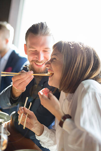 Feeding with sushi Friends eating sushi in restaurant, lens flare chopsticks photos stock pictures, royalty-free photos & images