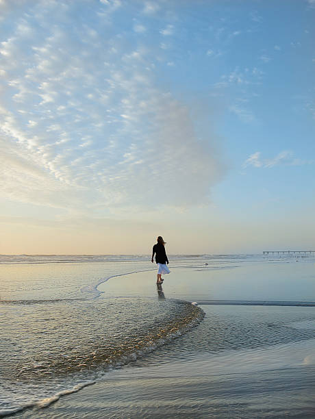 istock Woman walking on the beach at sunrise. 519493936