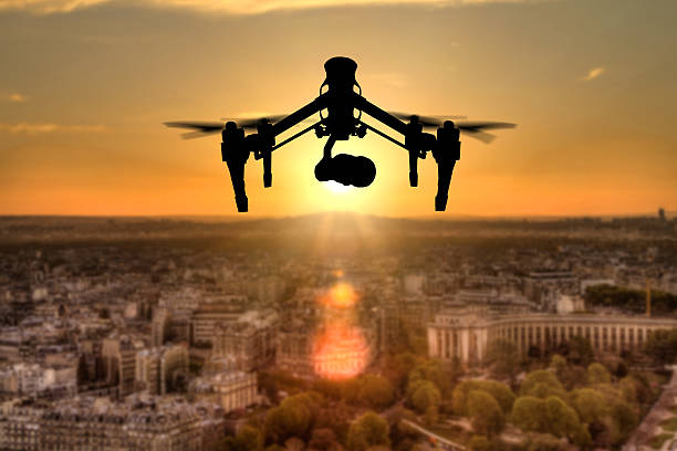 Drone silhouette flying above Paris city panorama in sunset