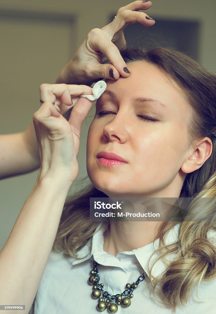 Make-up artist cleaning skin on model's face. Adult Stock Photo