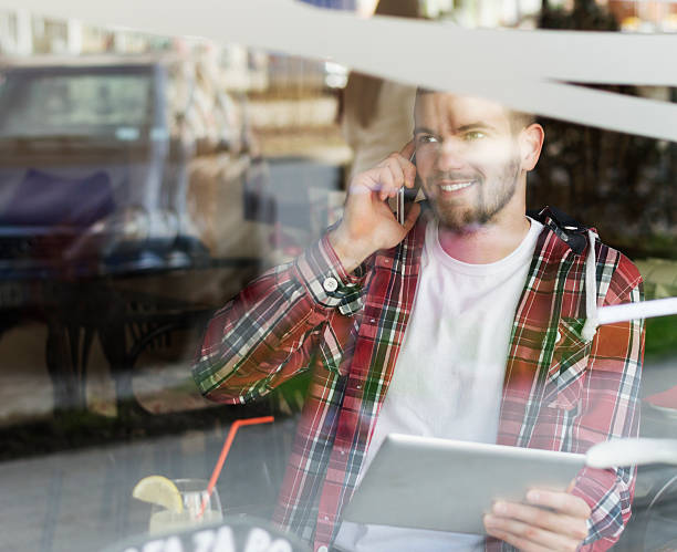 istock Cheerful young man talking on smart phone at cafe 519502270