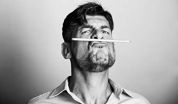 Photo of Mad artist holds a pencil with his lips