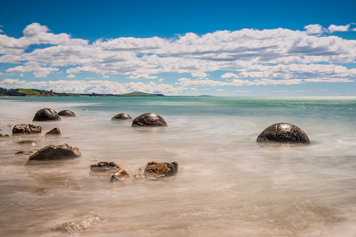 Long exposure image of Moeraki Boulders lying along a stretch of Koekohe Beach on the wave-cut Otago coast of South Island New Zealand. These formations are a major tourist attraction of the area.