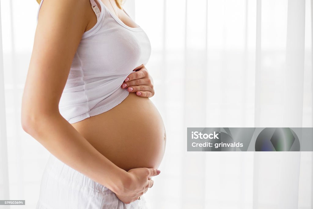 Pregnant woman standing next to window Pregnant woman standing next to window  Pregnant Stock Photo