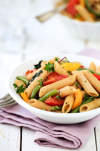 Delicious vegetarian whole wheat pasta penne with green beans, yellow bell pepper, cherry tomatoes and spinach