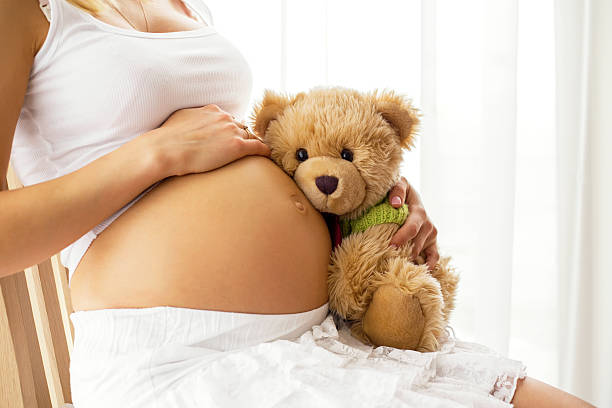 istock Pregnant woman holding teddy bear 519505794