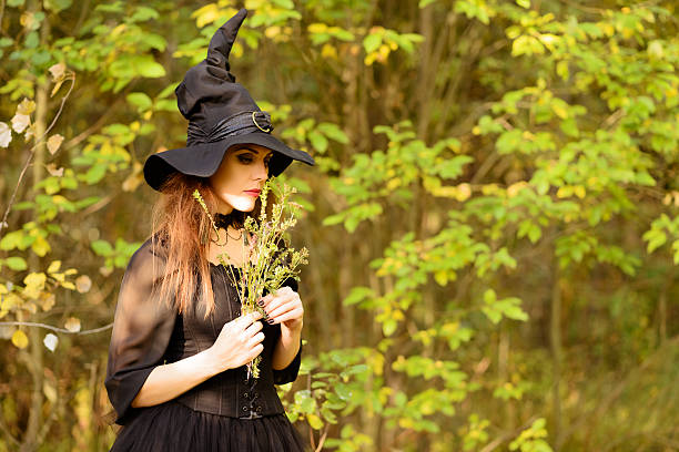 istock woman in witch's hat, smelling weeds in hands 519507707