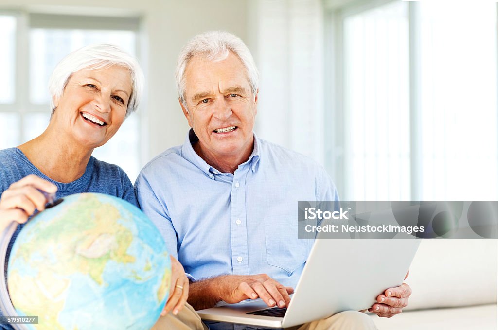 Couple With Laptop And Globe Planning Vacation At Home Portrait of senior couple with laptop and globe planning vacation at home. Horizontal shot. 60-64 Years Stock Photo