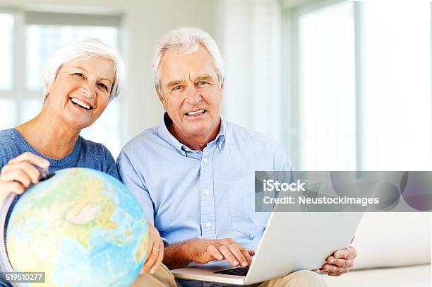 Couple With Laptop And Globe Planning Vacation At Home Stock Photo - Download Image Now