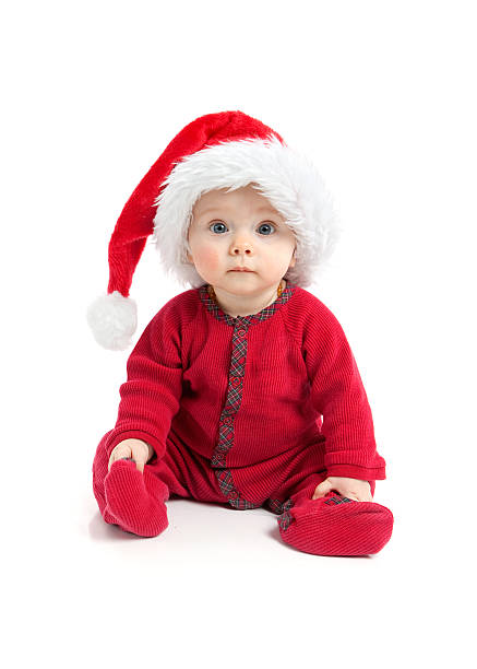 Cute baby wearing red and a Santa hat sitting on white background.