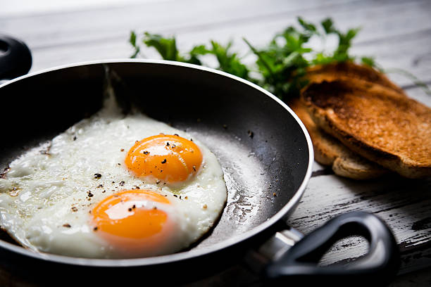 жареные яйца и поджаренный хлеб - preparing food indoors horizontal close up стоковые фото и изображения