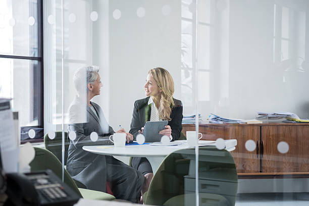 istock Two female colleagues sitting behind glass partition in modern office 519523508