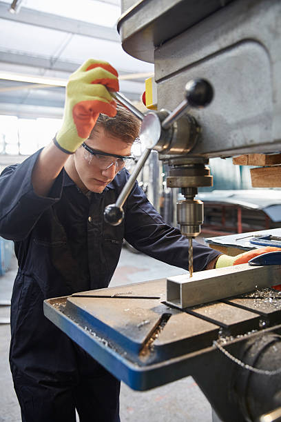 istock Young apprentice using pillar drill in steel fabrication factory 519526720