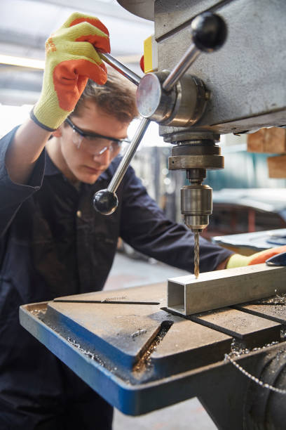 istock Young apprentice using pillar drill in steel fabrication factory 519526800