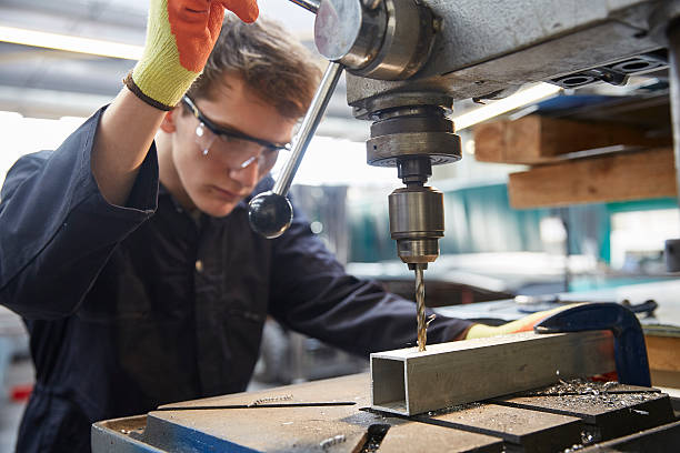 istock Young apprentice using pillar drill in steel fabrication factory 519526968