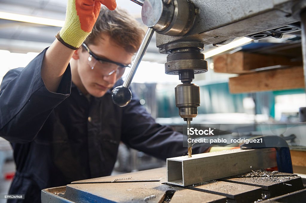 Young apprentice using pillar drill in steel fabrication factory Trainee Stock Photo