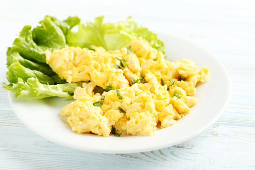 Scrambled eggs with vegetables on a blue wooden table