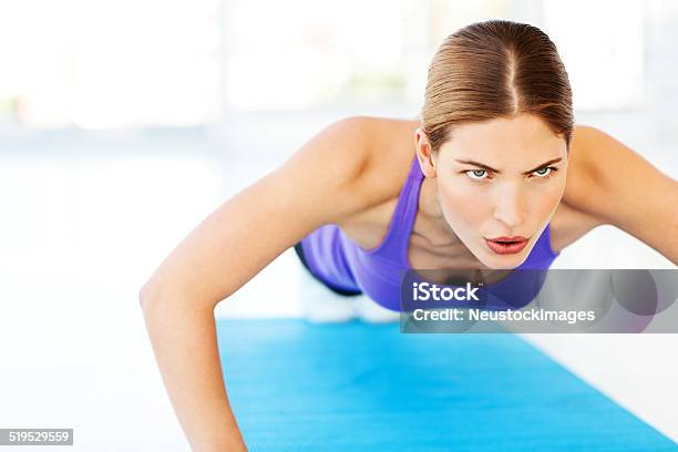 Determined Woman Doing Pushups On Exercise Mat In Gym Stock Photo - Download Image Now