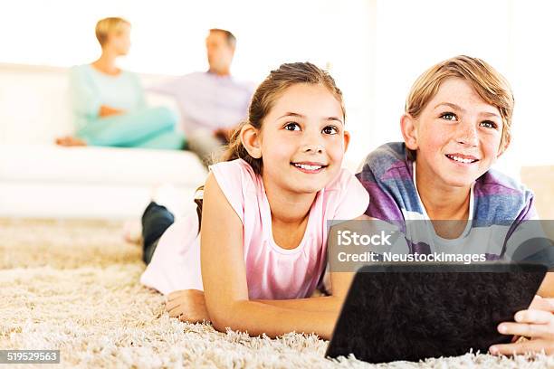 Siblings With Digital Tablet Looking Away At Home Stock Photo - Download Image Now - 10-11 Years, 30-34 Years, 30-39 Years
