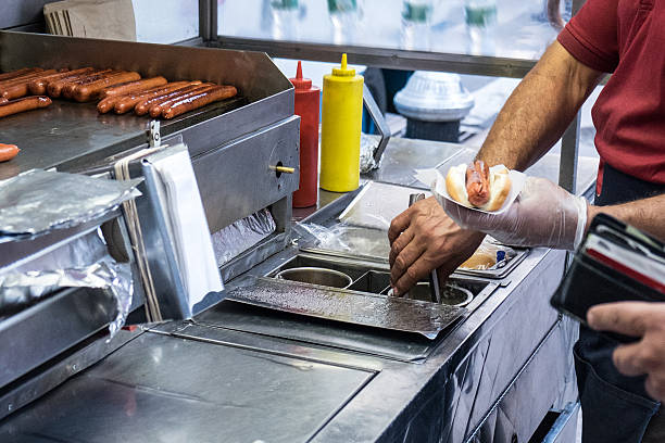 Street hot dog man holding a hotdog out in New York City hot dog stand stock pictures, royalty-free photos & images