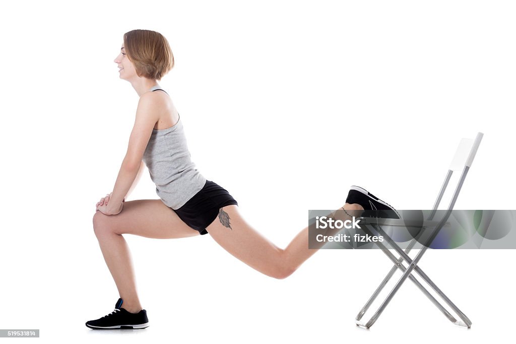 Sporty woman fitness training Young cheerful sporty attractive woman doing fitness training, exercises for hips and buttocks with office chair, full length isolated studio image on white background Chair Stock Photo