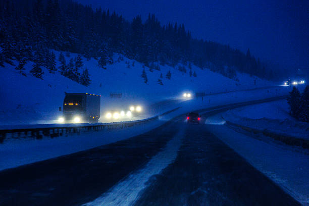 Speeding semi-truck and car traffic on the treacherous, snow blizzard slippery Colorado, USA Interstate Route 70 expressway over the Rocky Mountains in the dead of winter. Dark, gritty, high ISO late evening dusk motion blur. NOTE: Extreme grain!