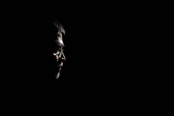 Portrait of a senior man in dark background. Portrait of a senior man wearing glasses. Very dramatic lighting in this image. The background is jet black. hopelessness photos stock pictures, royalty-free photos & images