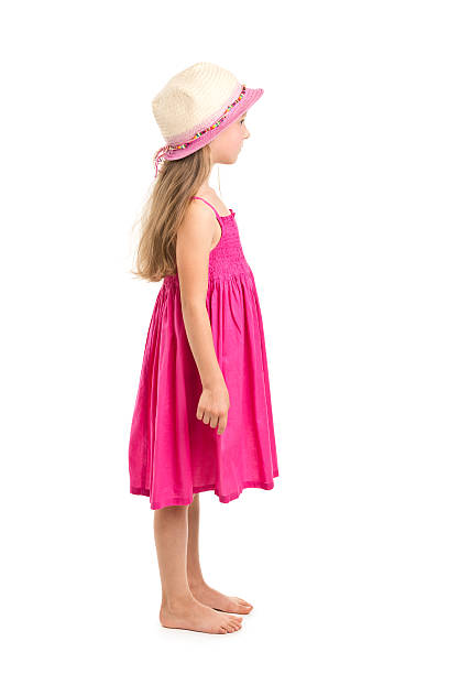 Full length shot of beautiful young blonde girl in big pink floppy hat, a polka dot dress and flip flops. Isolated on white studio background