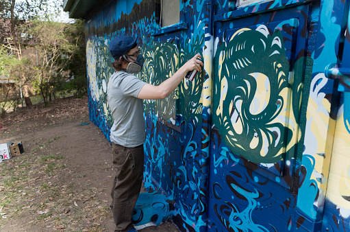 Blue Mountains, Australia - October 8, 2014: Council commissioned graffiti artist painting a wall in the Blue Mountains of Australia